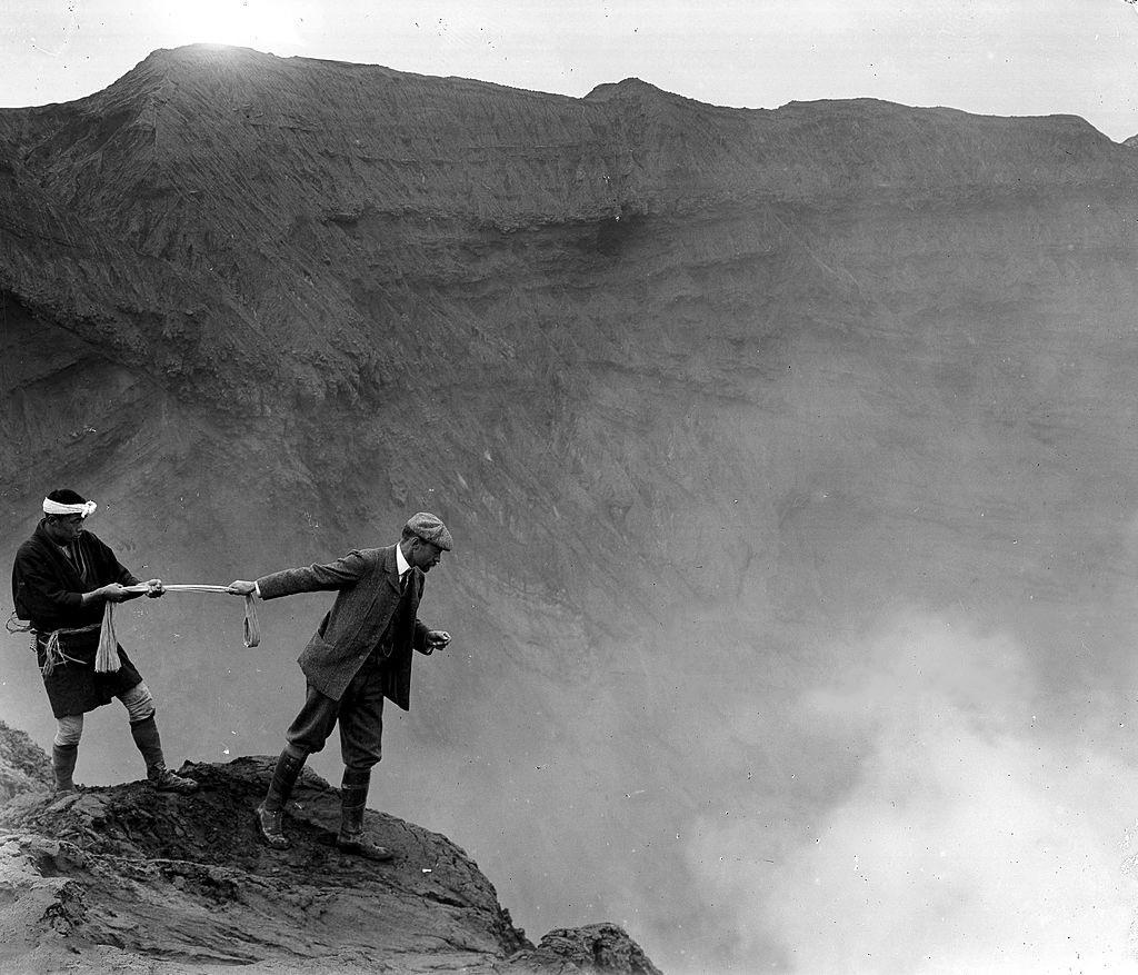 A man leaning over the edge to look over in to the crater of Aso San mountain, Kyushu, Japan, ca. 1906. Photo by Herbert Ponting.jpg