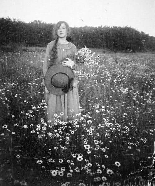 Young woman in a field of flowers, 1900's.jpg