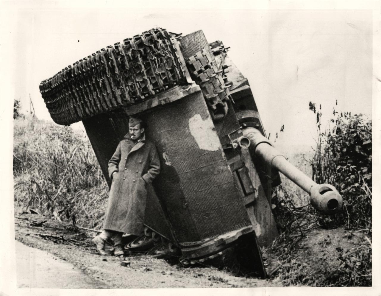 British soldier protecting himself from the rain under turned over tank, Italy, 1944.jpg