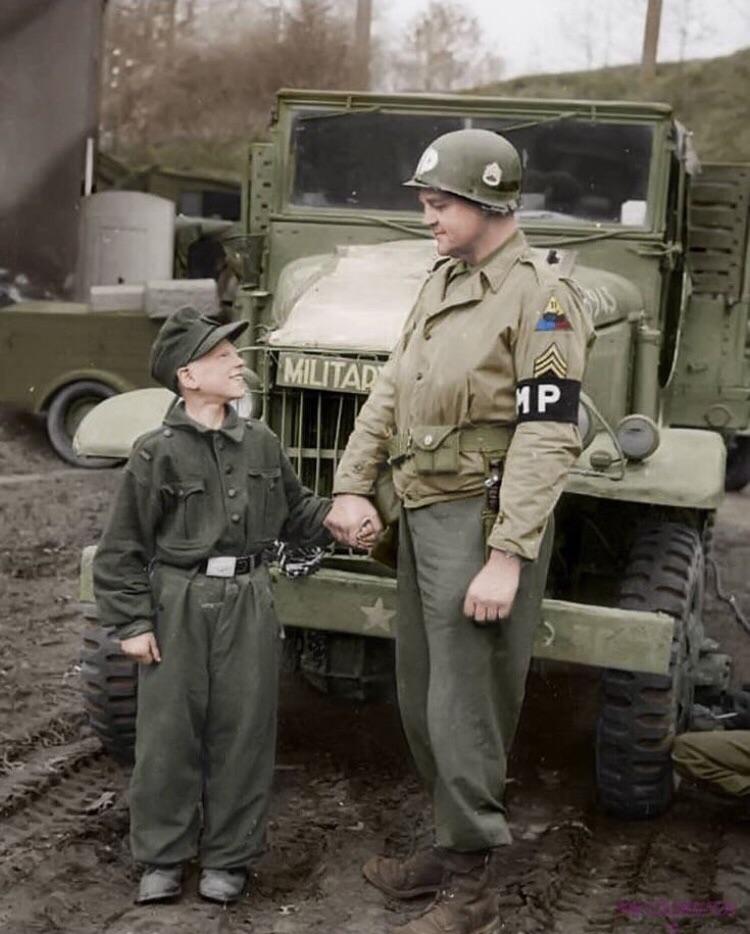 US Staff Sergeant Francis Daggertt of Military police of the 11th armoured division with a young Wehrmacht soldier , the German only had 10 years old when captured in the city of Kronach on April 27, 1945.jpg