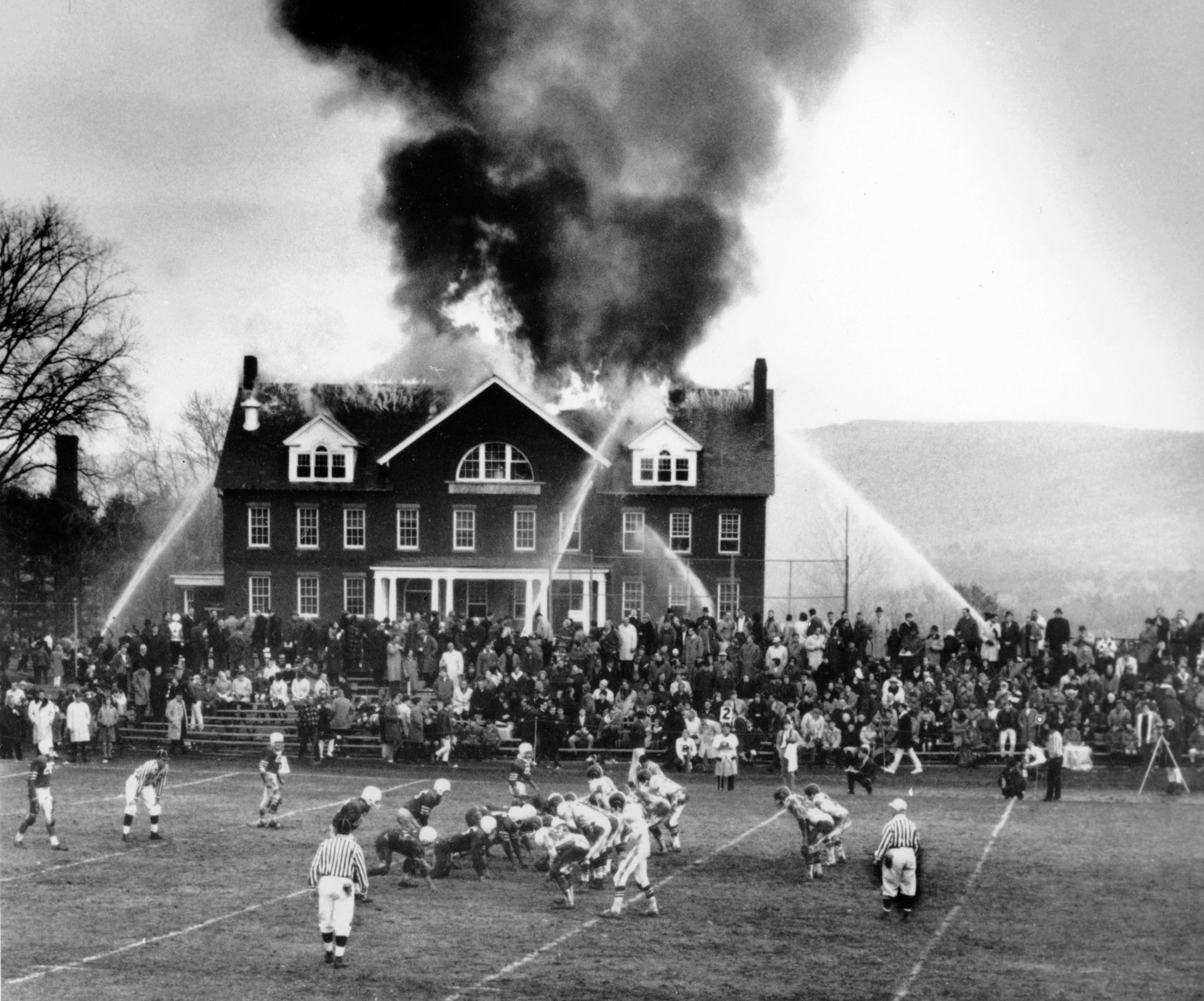 A high school football game continues as one of the home team’s school buildings burns in western Massachusetts, 1965.jpg