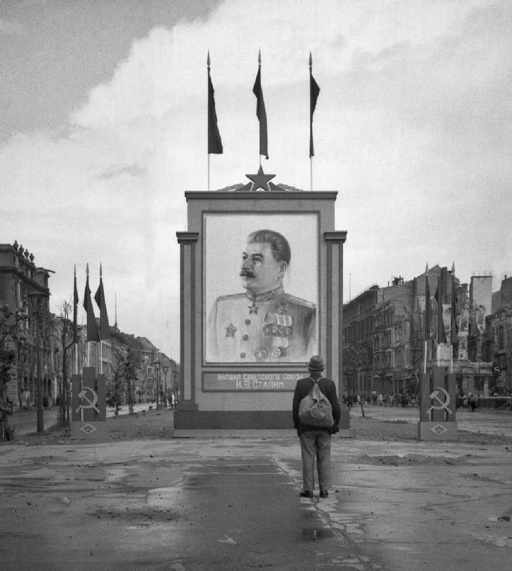 A German civilian looks at a large poster portrait of Stalin at center of Berlin,3 June 1945.jpg
