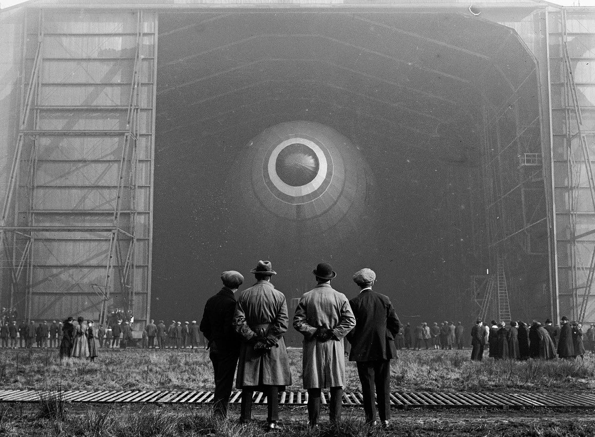 A crowd watches British Airship R-33 emerge from the hanger for her maiden flight - 1919.jpg