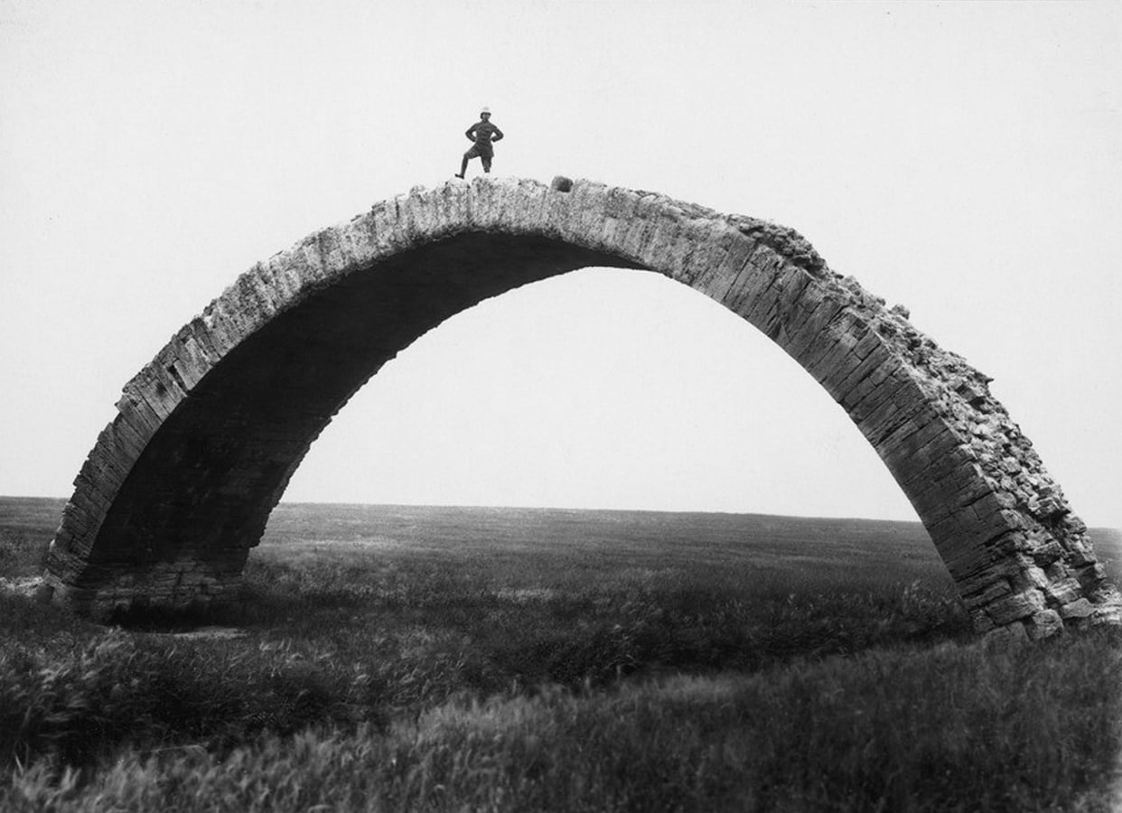 German archaeologist Max von Oppenheim standing on top of an arch of the remains of a Roman bridge near Mosul. Iraq, 1937.jpg