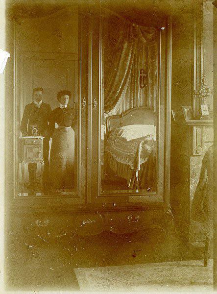 A couple taking a photo of themselves in their bedroom, late 1800s.jpg