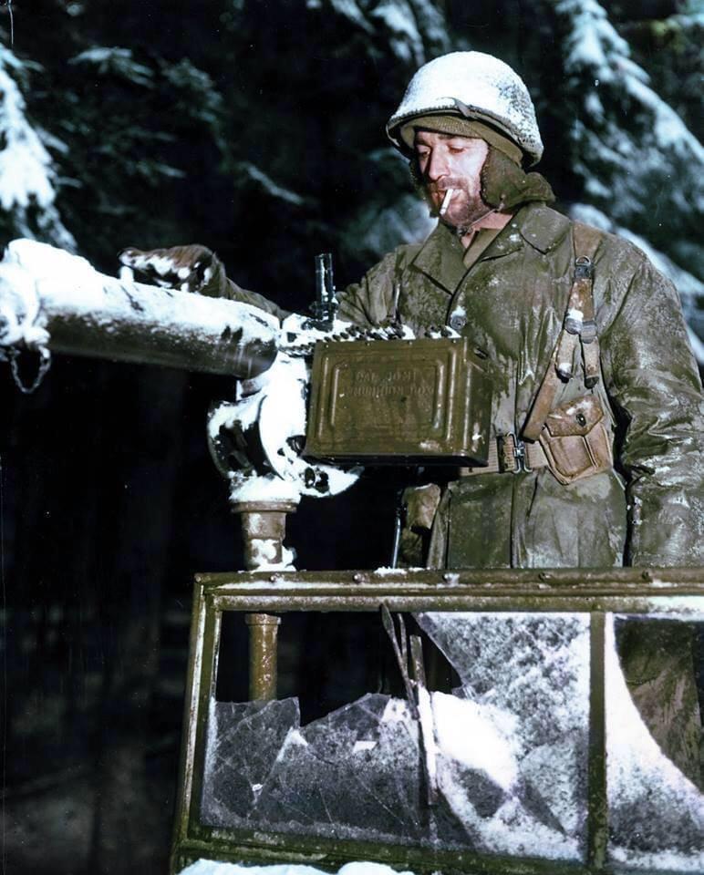 Private Charles Preston, of Nicholasville, Kentucky, brushes snow from a 30-caliber machine gun mounted on his jeep. His unit is moving against the German counterattack in the Ardennes during the Battle of the Bulge. December 21, 1944.jpg