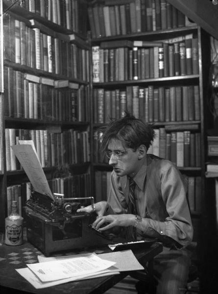 Robert Albert Bloch, author of Psycho, surrounded by tall bookshelves full of books 1950s.jpg