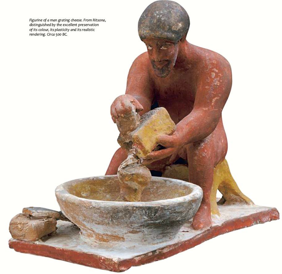 A painted figurine of a man grating cheese. C. 500 BCE, now housed at the Archaeological Museum of Thebes in Greece.jpg