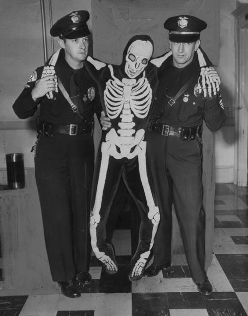 Cops arresting a drunk dude in a skeleton costume 1950.jpg