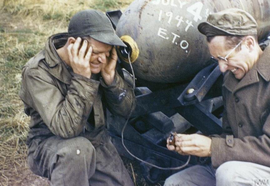 Sergeant Russell Butts and Sergeant Robert Sand, ground crew of the 55th Fighter Group, pretend to light the fuse on a 500-pound bomb in July, 1944.jpg