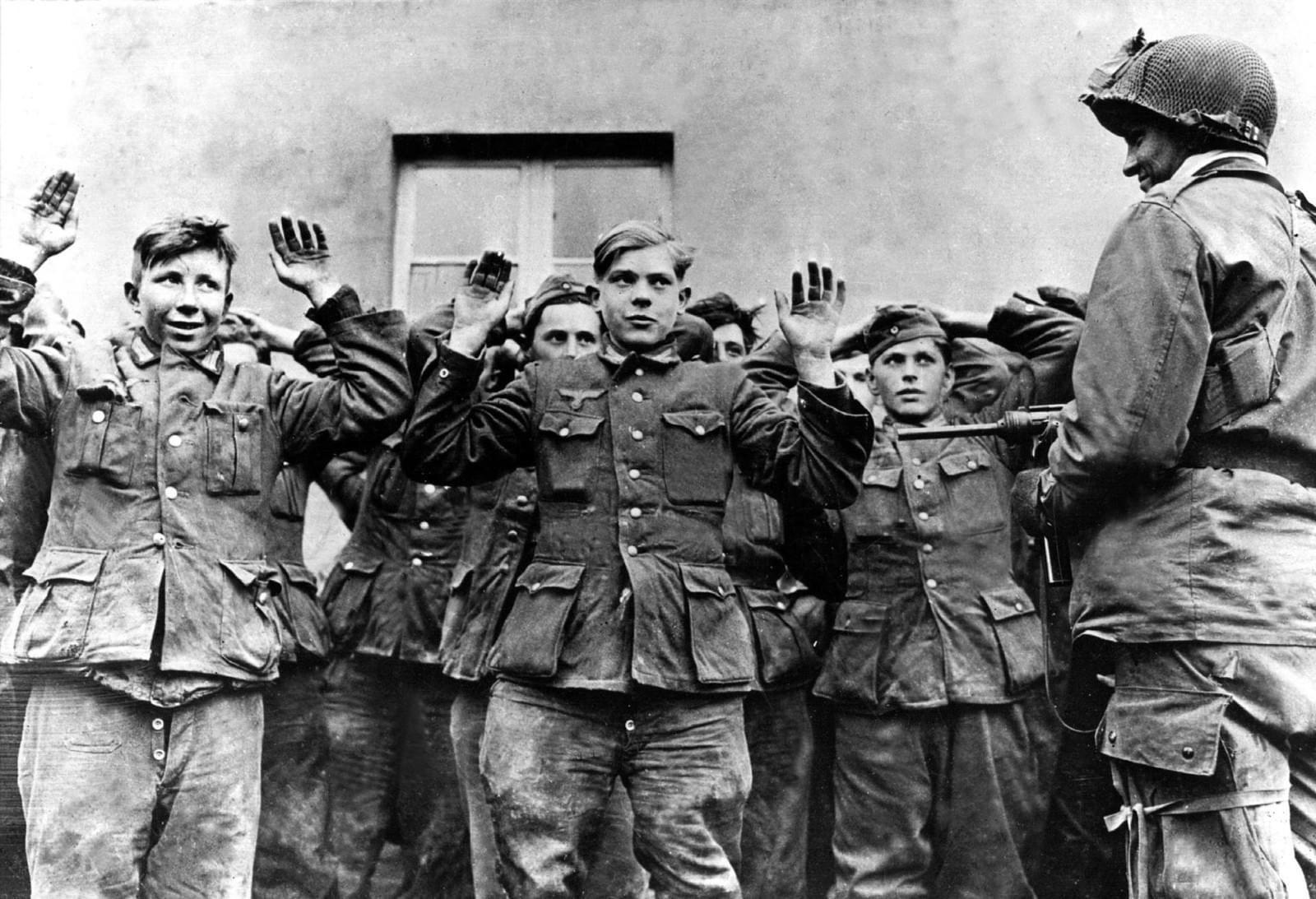 Private Herbert Norman of the US 17th Airborne Division keeps a watchful eye on a group of young Wehrmacht soldiers taken prisoner near Münster, Germany, 1945.jpg