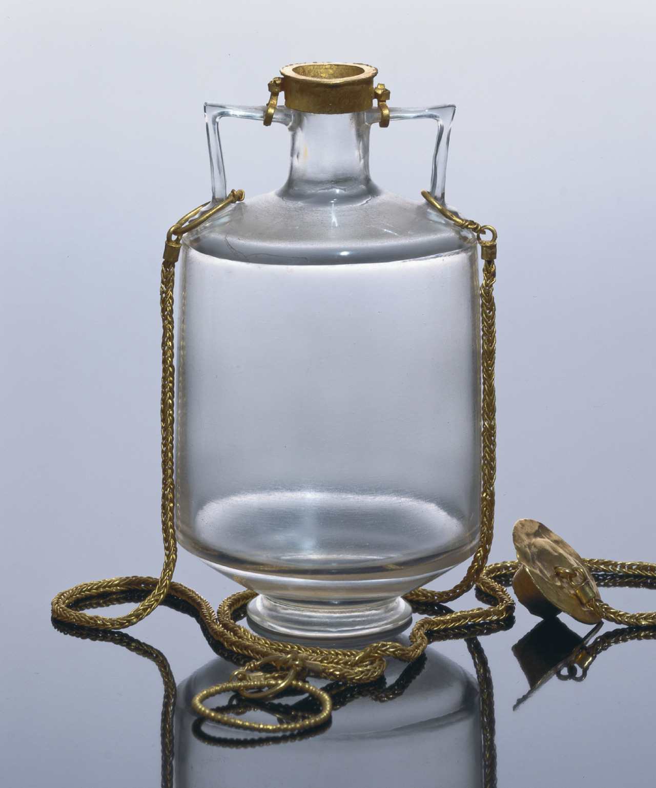 This small, thin-walled perfume jar (Amphoriskos) was ground out of a block of transparent rock crystal and fitted with a gold cap and braided gold chain. A costly vessel, it would have originally belonged to a Roman lady, 1-50 AD.jpg
