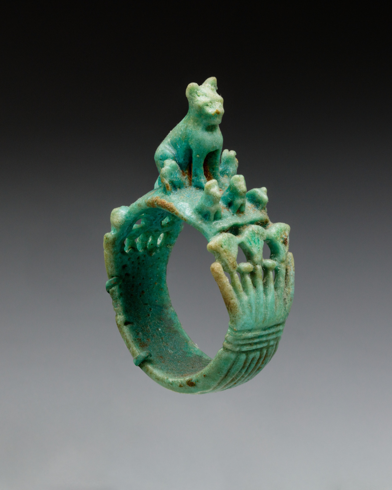 Egyptian faience Ring from 1295-664 BC, with a cat and kittens perched above flowering papyrus. Possibly linked to the myth of the 'Faraway Goddess'.jpg
