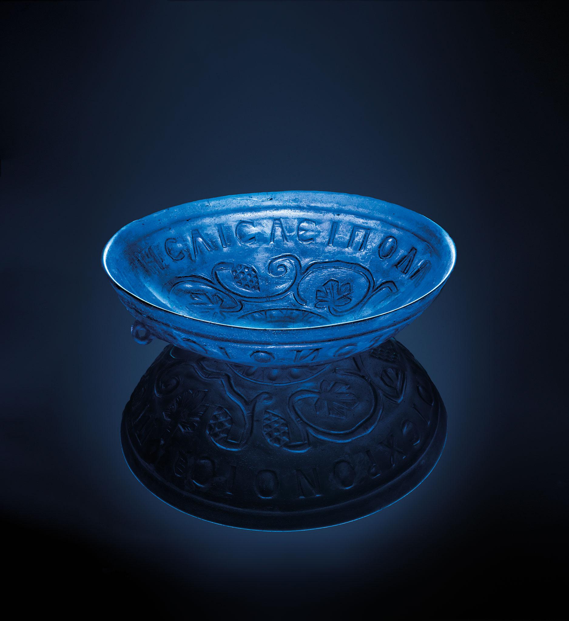 Blue ornate glass bowl found in a Roman cemetery in Slovenia. Its Ancient Greek inscription translates to Drink to live forever, for many years. 4th century AD, City Museum of Ljubljana.jpg