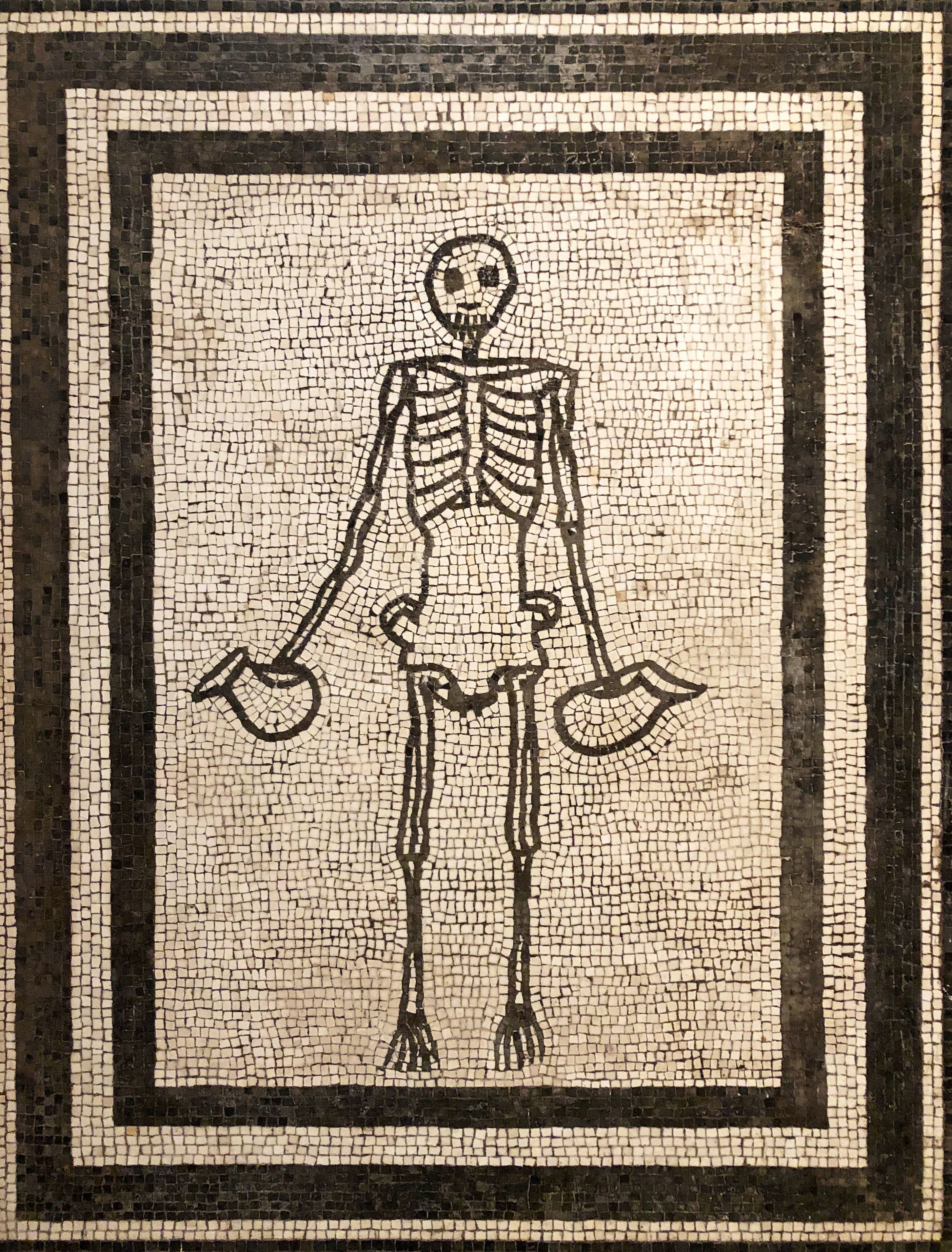 Roman mosaic at the House of Polybius in Pompeii, showing a grinning skeleton holding a wine jug in each hand.jpg
