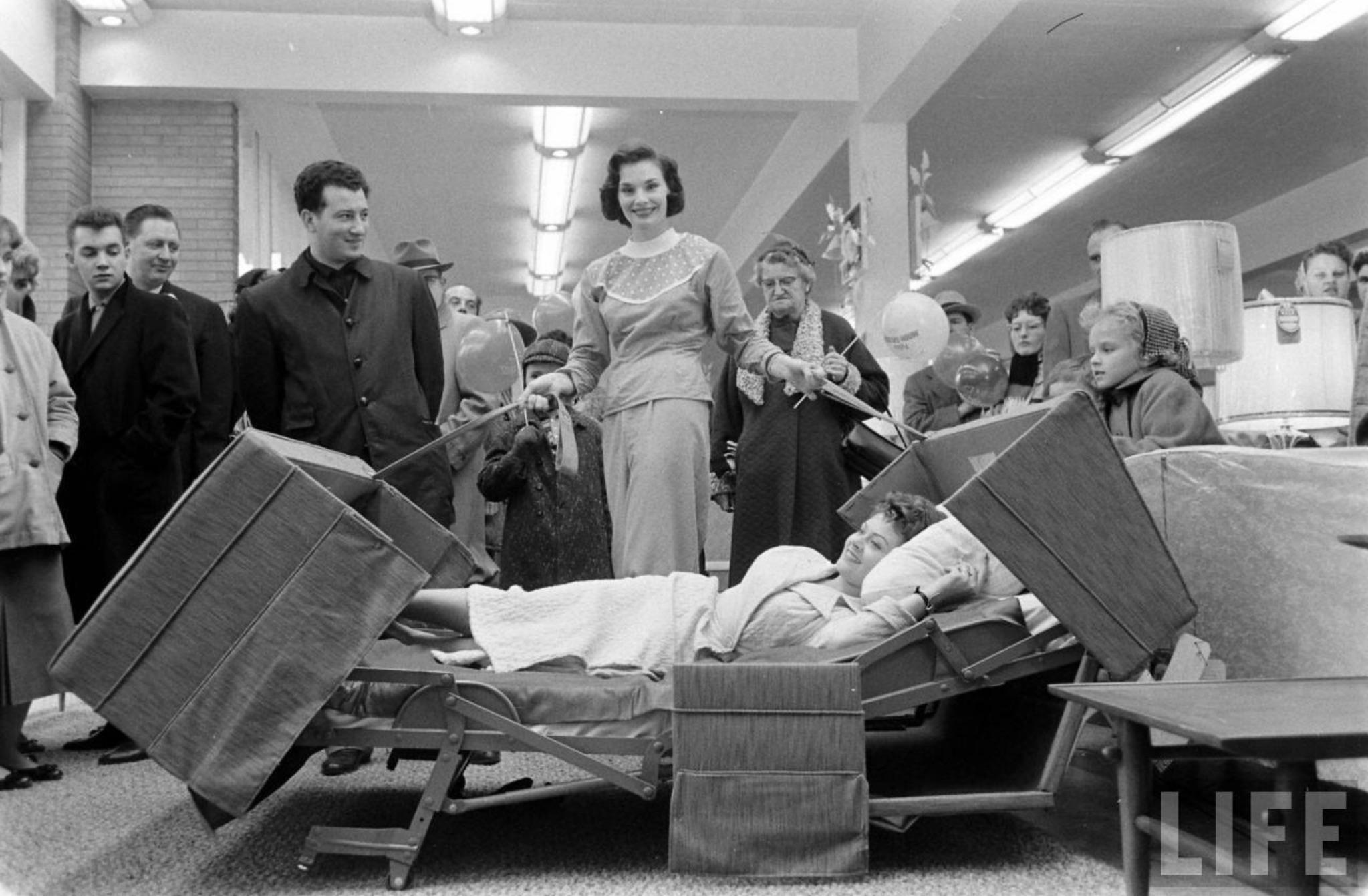 Demonstrating a couch that converts into a bed at Polk Brothers (Francis Miller. 1958).jpg