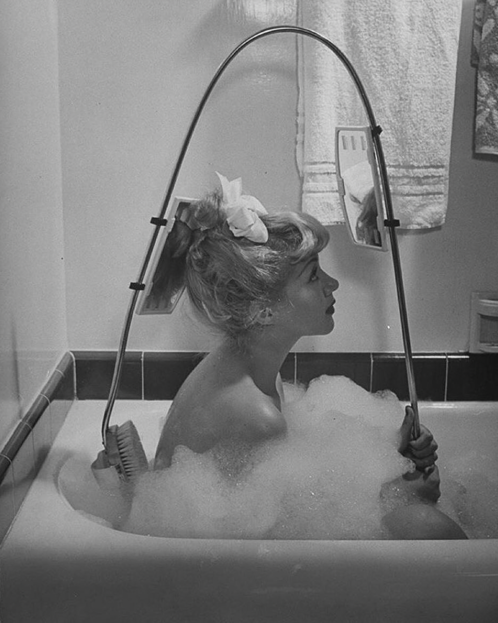 1947. A woman uses a new innovative crooked back brush, marketed by Los Angeles Brush Manufacture Inc., equipped with front and rear view mirrors so that she may see where she is scrubbing.png