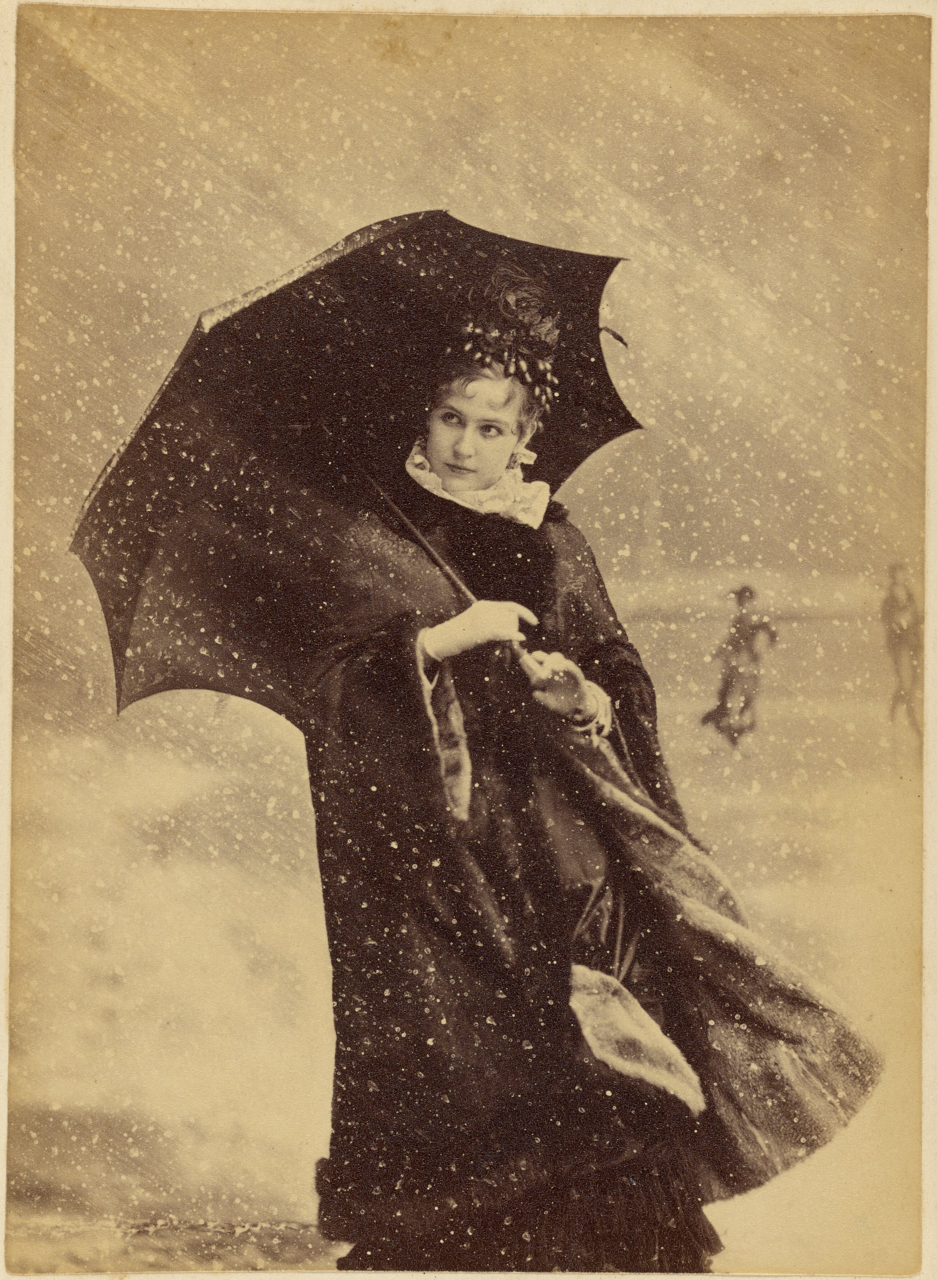 Woman with an umbrella in a snow storm, circa 1885.jpg