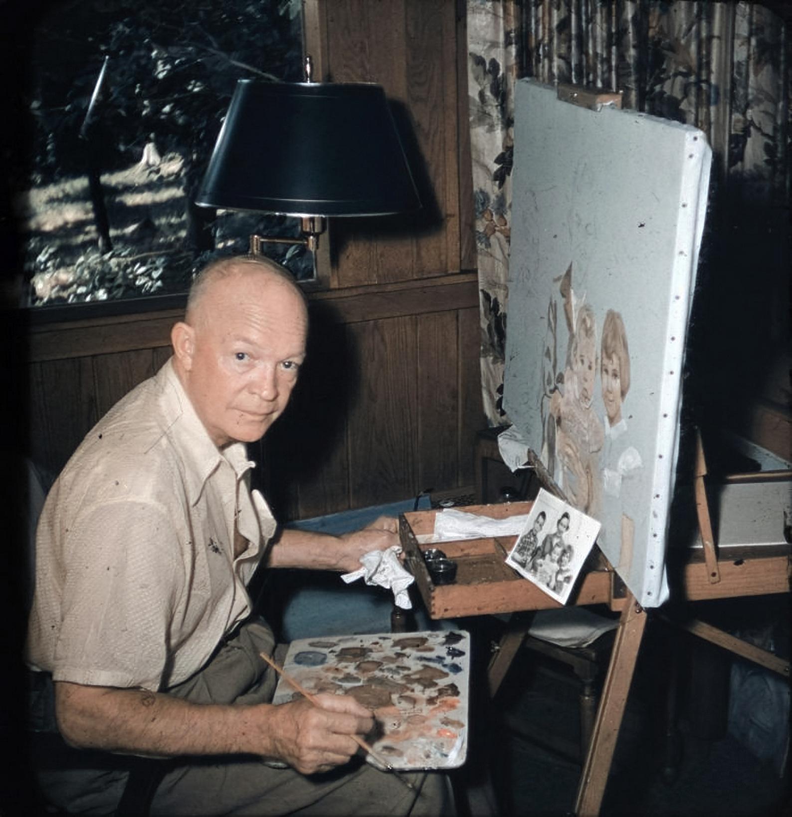 President Eisenhower pauses for the camera as he works on a painting of his daughter-in-law Barbara and grand children David, Anne, and Susan, 1954.jpg