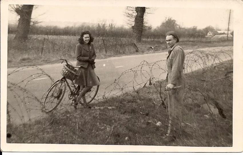 Sgt. Robert Martin 'Bob' Waddell, an American bomber mechanic with the 323rd Squadron, talking with a local British girl who rode by his base at Bassingbourn. They were later married. (1943).jpg