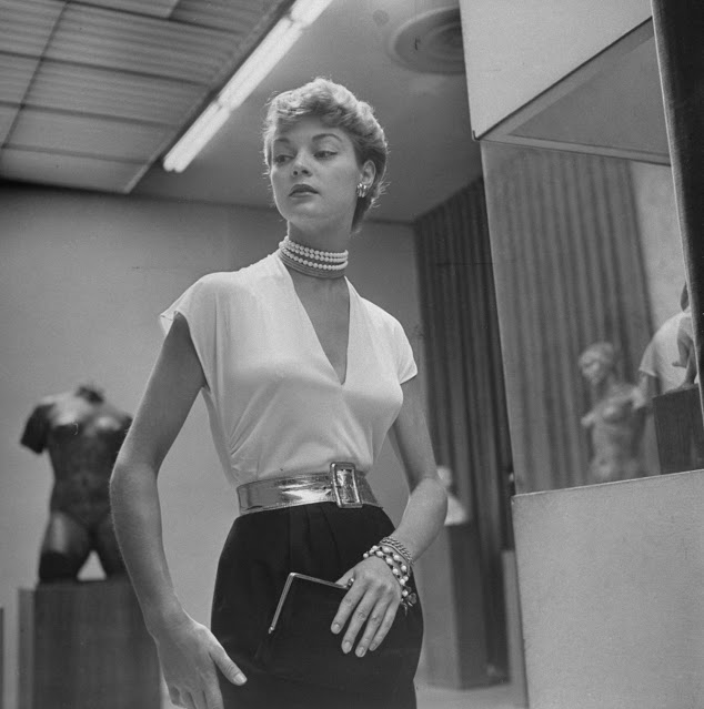 Jean Patchett modeling earrings (25 cents), a necklace (94 cents), a bracelet ($1.00) and earrings (25 cents), setting off a white rayon blouse (98 cents) for a story on dime-store fashion, 1949.jpg