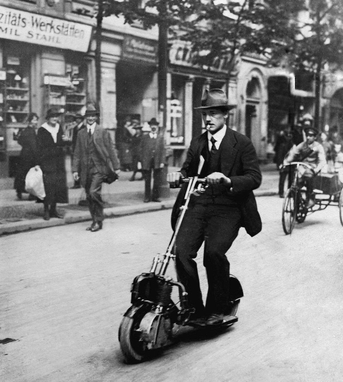 (1915) man smoking a cigar on the worlds first electric scooter The Autoped.jpg