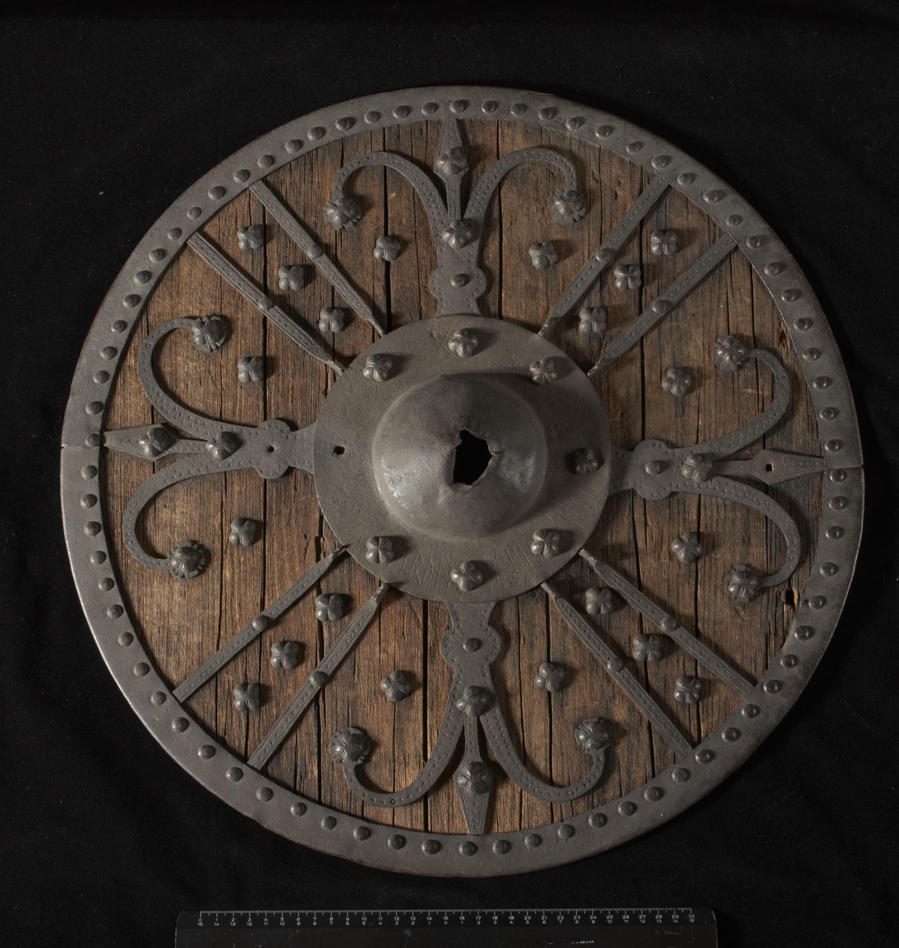 Medieval shield made of wood and iron, found in Sætesdalen, Norway [1200 CE ca]. It bears a runic inscription around the bulge. Oslo Kulturhistorisk museum, nr. C954.jpg