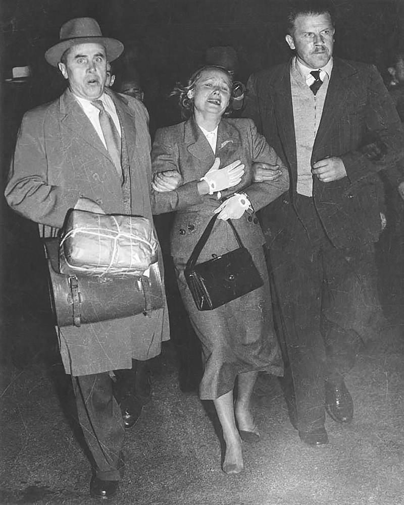Evdokia Petrova at Mascot Airport, Sydney, being escorted to a plane by two armed Soviet diplomatic couriers (19.04.1954)..jpg