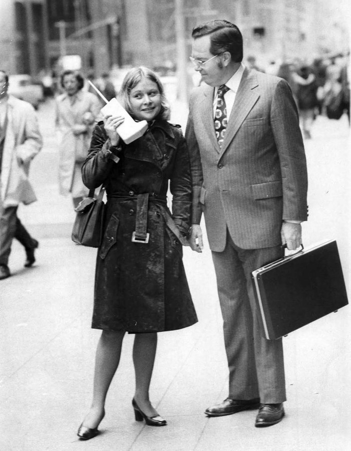 Jeanne Bauer walks with a DynaTAC mobile phone on 6th Avenue in New York, accompanied by John Mitchell, the Motorola engineer behind the phone. (1973).jpg