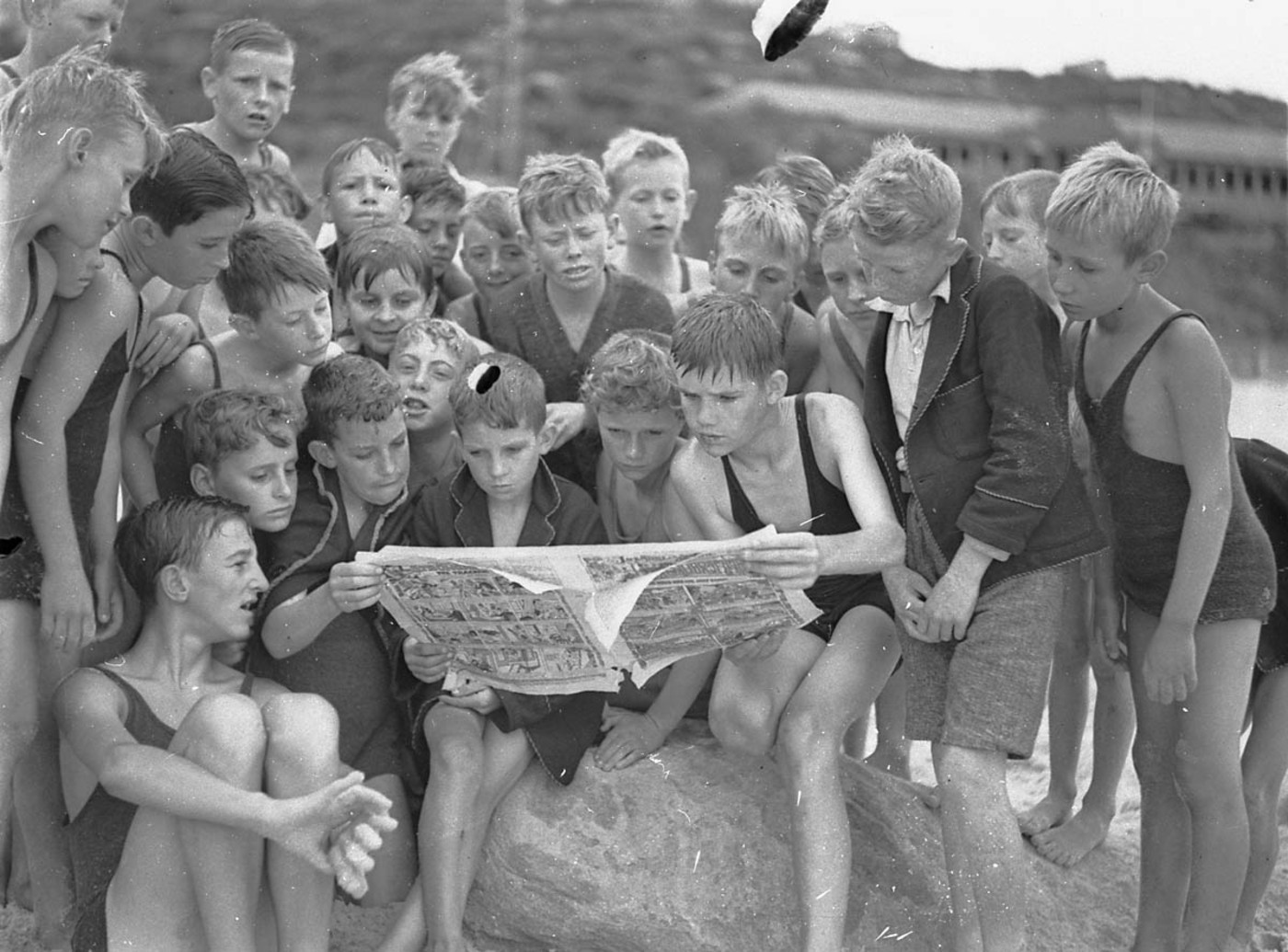 Stewart House boys looking at comics from a Sunday paper, South Curl Curl Beach, by Sam Hood, 10 January 1935.jpg