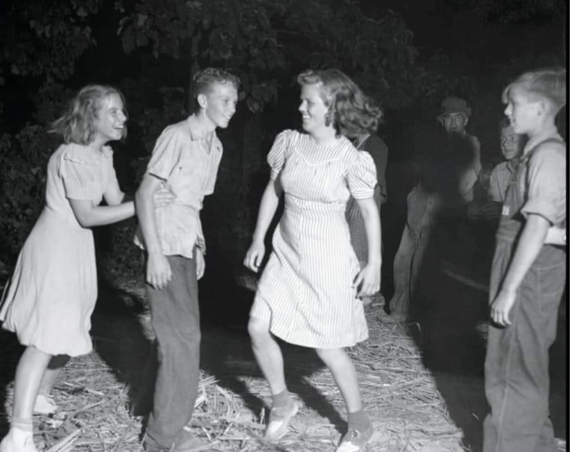 Young lady pushes a young man towards a love interest at a dance, Claiborne County, Tennessee, late 1930s.jpg