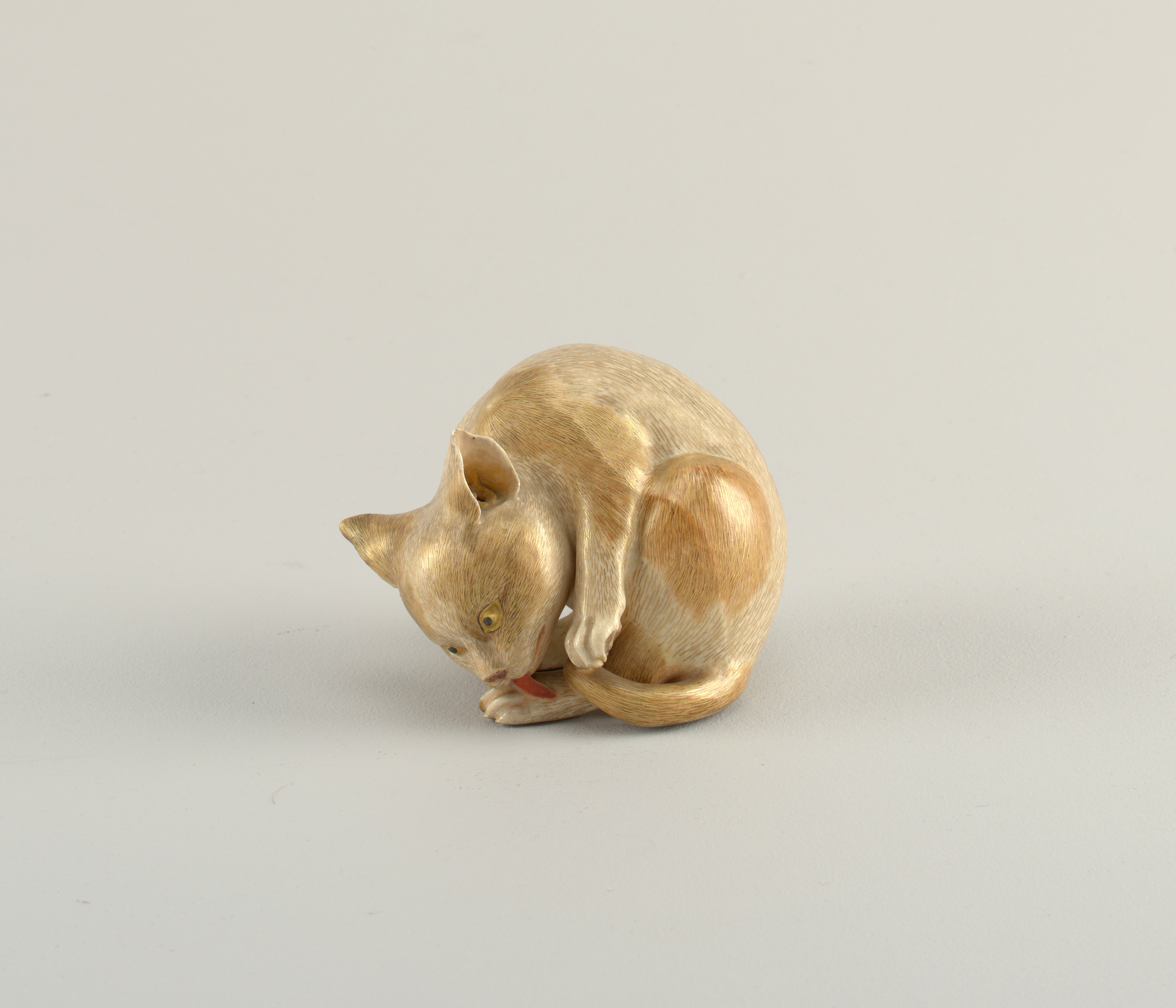 Satsuma-style painted stoneware cat sculpture featuring the cat licking its back paw, Japanese, 1904.jpg