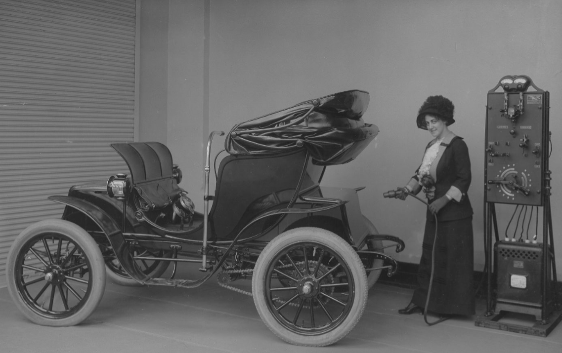 Woman with rectifier and electric car 1912.png