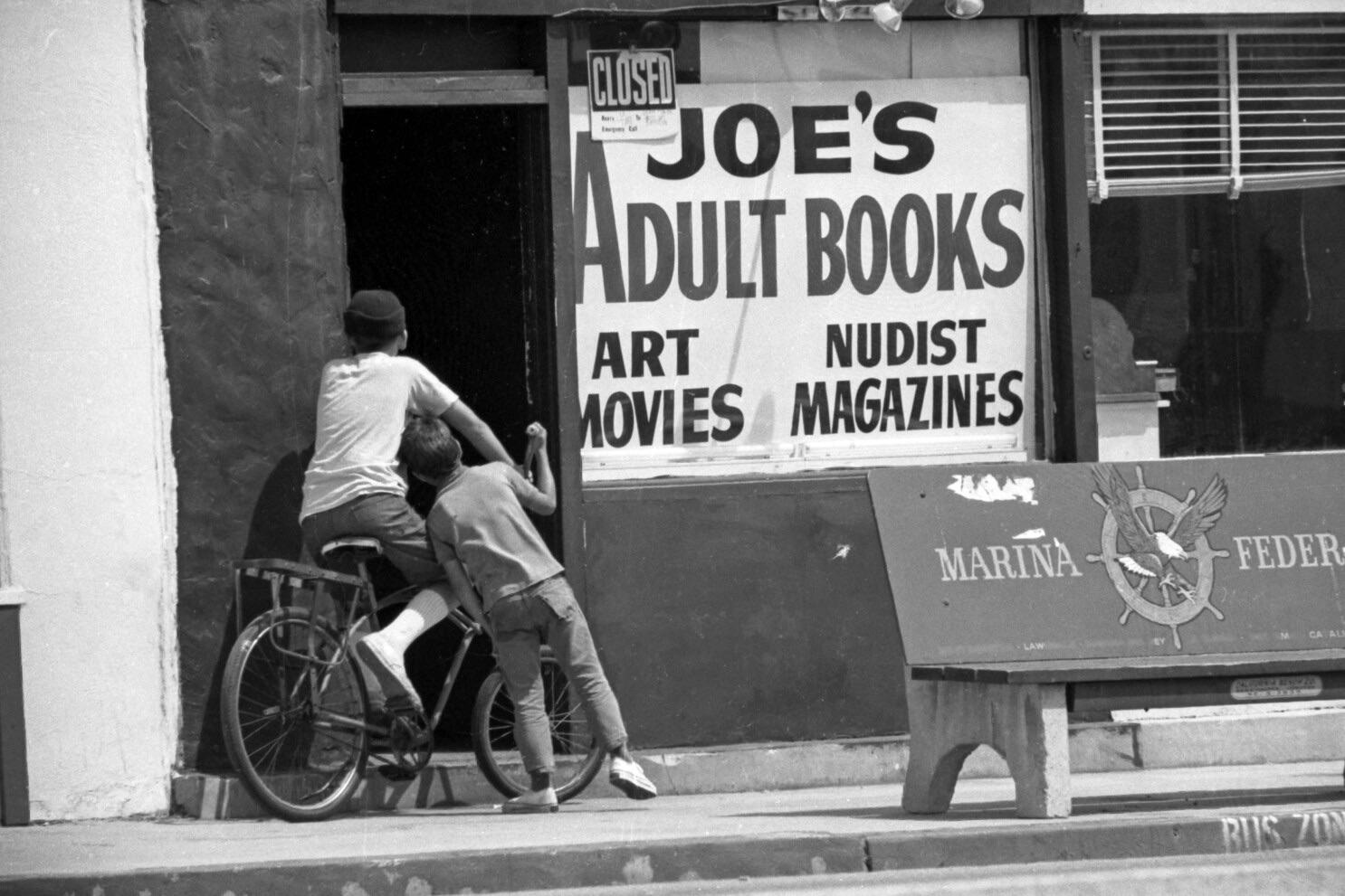 Two boys stop to investigate an adult book store in Lennox, Los Angeles. August 1969.jpeg