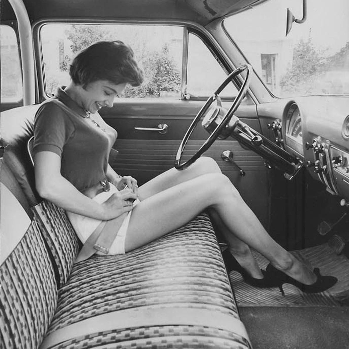 Woman inspecting this new thing, the security belt in her car, circa 1950s.jpeg