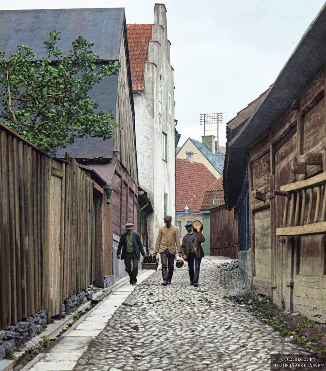 Three men carrying alcohol on St Drottensgatan, a street in Visby, Gotland, Sweden in ca 1900.jpeg