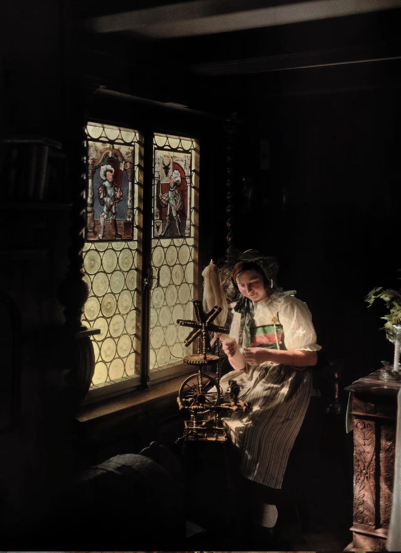 Unknown woman working at spinning wheel in a home in Lucerne, Switzerland, 1932. the window is beautiful. Not colorized, autochrome lumiere.jpeg