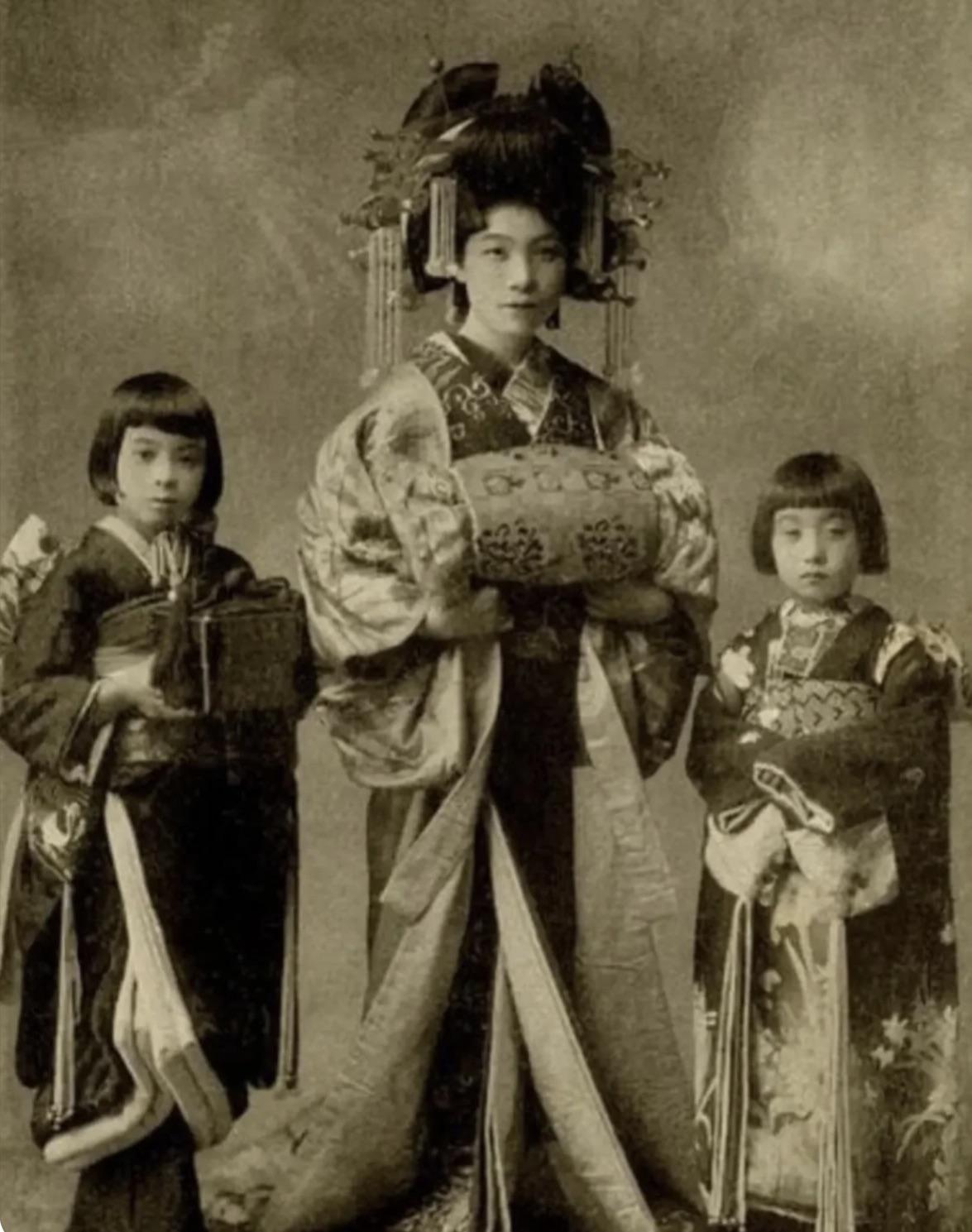 A Tayu( high ranking Japanese Courtesan) with her two Kamuro( Child attendant trainees) 1910s.jpeg